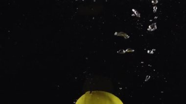 Düşen su besinleri. Limon sıçrama balonu. Suda yüzen taze narenciye. Siyah arka planda izole edilmiş.