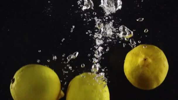 Spritzende Zitronen Die Isoliert Über Schwarzem Hintergrund Wasser Treiben — Stockvideo