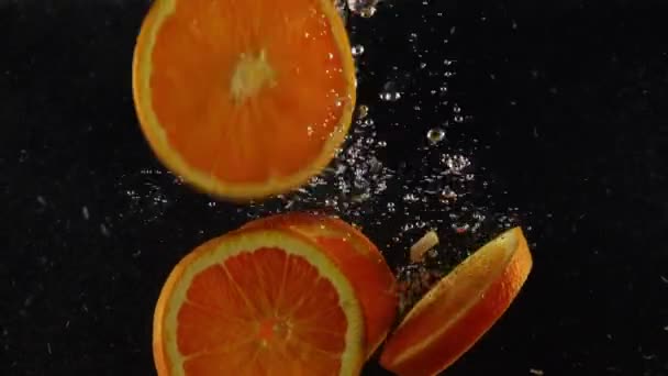 Оранжевые Ломтики Падают Падают Чистую Воду Пузырьками Заднем Фоне — стоковое видео