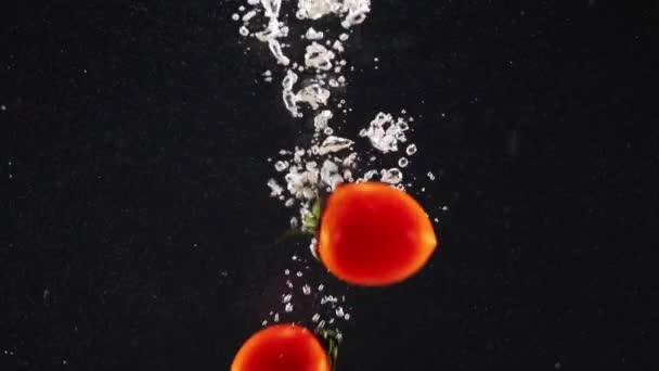 Rote Tomaten Fallen Wasser Mit Blase Isoliert Über Schwarzem Hintergrund — Stockvideo