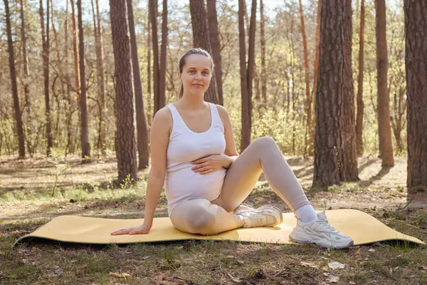 스포츠 숲에서 매트에 요가를 여자를 임신과 자연을 즐기는 카메라를 스톡 이미지