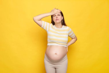 Çıplak göbekli, sağlıksız, beyaz bir kadın. Sarı arka planda tek parça giyinmiş. Acı çeken kafasına dokunmaktan yorgun düşmüş.