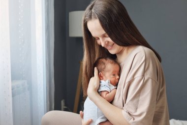 Sevimli yeni doğmuş bebek anne kollarında dinleniyor emniyette ve sağlıklı yeni doğmuş bebek anne ile bebeğini nazikçe emziriyor.