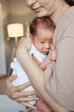 Sakin, yeni doğmuş bir bebek annesinin kucağında huzur içinde uyuyakalıyor. Kadın, anne olmanın ilk günlerinden zevk alıyor.