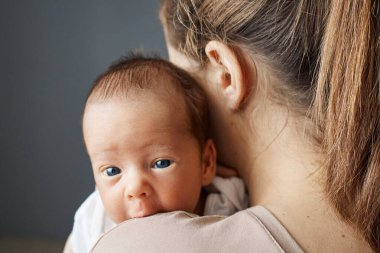 Tanımlanamayan bir anne kucağında yeni doğmuş bir bebeği evde ona bakıyor. Sevgi dolu bir anneyle uyuyan bir çocuk.