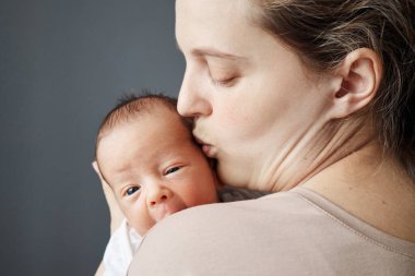 Çocuk doğurmak ve ebeveynlerin sevmesi. Annesinin kucağında bir bebek, kucağında yeni doğmuş bir çocuk ve yanağından öpüyor. Annesinin kucağında mutlu sıcak anlar, bebeğiyle birlikte.