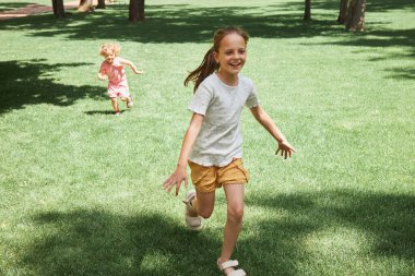 Mutlu Kafkasyalı gülen çocuklar parkta çimde koşuşturan kız kardeşler yaz tatilinde birlikte dinlenmenin keyfini çıkarıyorlar. Hafta sonları zaman gönderiyorlar.