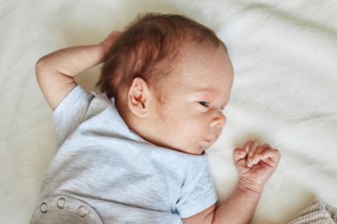 Yeni doğan bebek uykuya dalıyor. Bebek beyaz çarşafta yatıyor. Reklam için boş bir alan.