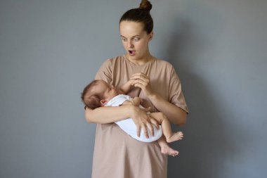 Yeni doğmuş bebeğini tutan beyaz saçlı kadının gri arka planda dikilip koca gözlü ve ağzı açık küçük kızına ve oğluna bakmasına şaşırdım.