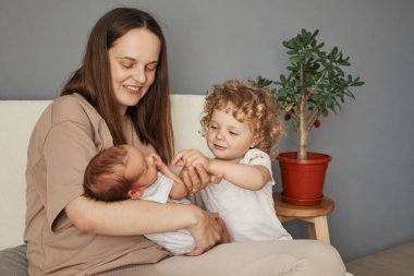 Neşeli ve sevecen bir aile. Gülümseyen Kafkasyalı anne yeni doğmuş çocuğuyla nişanlanıyor ve büyük kıvırcık sarı saçlı kızı oturma odasında kanepede birlikte dinleniyorlar.