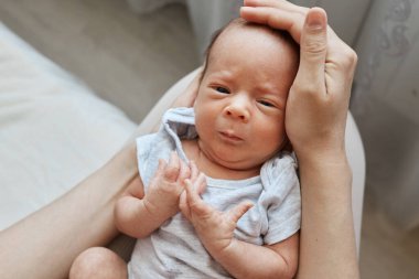 Sevgi ve şefkat ile dolu sağlıklı bebeğini kucaklayan, annesinin ellerinde güzel bir erkek bebek. Mutlu annelik anlarının tadını çıkarıyor.