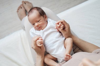 Bebeklerini kucağında tutan tanınmaz bir kadın. Bebeğin gelişini neşe ve dikkatle kutluyor. Güzel bir anı yakalıyor ve çocuğu uyutuyor.