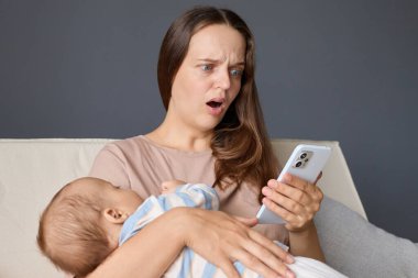 Korkmuş bir anne bebeğiyle birlikte oturma odasında poz verip kötü haberlerle mesajları okuyarak bebeğine bakarken internete bağlanıyor.