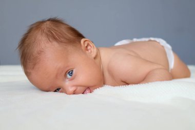 Sağlıklı yenidoğan yatağında sadece bez ile yatarken yüzünde tuhaf bir ifade, reklam için fotokopi alanı veya tanıtım içeriği var.