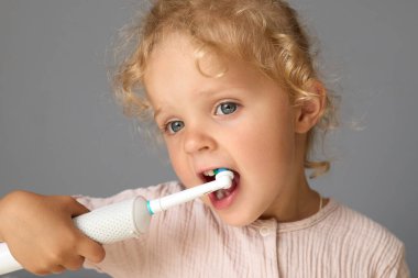 Küçük diş fırçası ve diş macunu kullanan, dişlerini fırçalayan, dişlerini fırçalayan güzel bir kız.