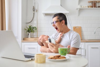 Uykulu, yorgun baba, çocuğunu kucağında tutuyor. Gezici iş platformlarında hokkabazlık yapıyor, serbest çalışıyor ve ebeveynlik yapıyor. Evdeki rahat mutfakta, masada oturuyor.