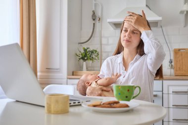 Hasta, yorgun bir kadın yeni doğmuş bebeği elinde tutuyor dijital görevler ve sosyal medyada çalışıyor doğum sırasında uzak işini yapıyor aşırı çalışma baş ağrısı çekiyor.