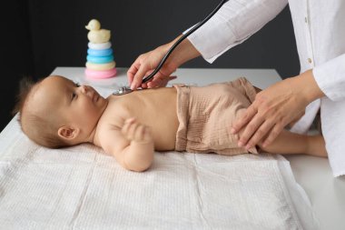Tanımlanamayan kadın pediyatrist, yeni doğan bebeğe steteskop kullanarak iyi donanımlı hastane odasında bebeğin sağlığını sağlama alıyor.