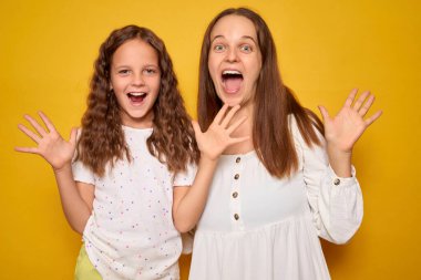 Oyuncu anne ve çocuk sarı arka planda izole edilmiş bir anne ve kızı yoğun duygular ve pençe benzeri hareketler gösteriyor neşeli ifadelerle reaksiyona giriyor.