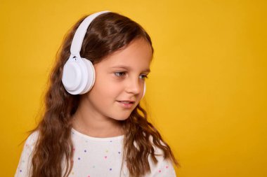 Kahverengi dalgalı saçlarıyla gülümseyen, kablosuz kulaklıkla müzik dinleyen, en sevdiği şarkıyı dinleyen ya da sarı arka planda kapalı bir yerde sesli kitap okuyan liseli kız.