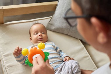 Yeni doğan gelişimi. Baba, evde geçirdikleri zaman boyunca sevgi gösterip eğlenirken mutlu bebeğiyle oturma odasında oynuyor.