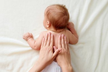 Kayropraktik manüel terapisti, bebeğin sırtını manipüle ediyor. Bebek masaj terapisi görüyor. Narin kaslarının evde tedavi görmesini ve rahatlamasını sağlıyor.
