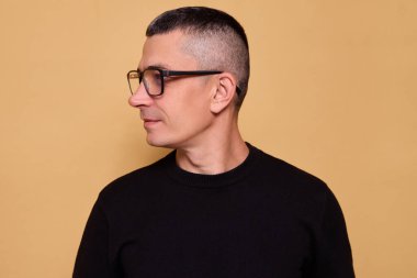 Gözlüklü ve rahat kazaklı gülümseyen bir adam büyüleyici bir gülümsemeyle içeri bakıyor neşeli enerjiyi hissediyor arkadaşça ve iyimser titreşimler yayıyor ve mutluluğu ifade ediyor.