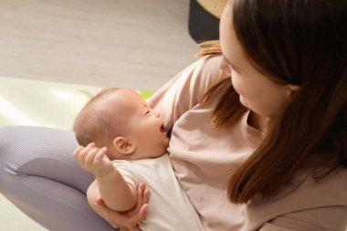 Anne 'nin ağlayan bebeğini kucaklamasını, onu sakinleştirmeye çalışmasını, üzgün bir kadının evde teselli edici dokunuşlarla çocuğunu sakinleştirmesini.