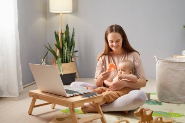 Sevgi dolu bir anne, bilgisayarını kullanarak serbest yaşam tarzını benimsiyor. Bu arada bebeği de oturma odasında yerde yatıyor. Uzaktan kumandalı işini yönetiyor.