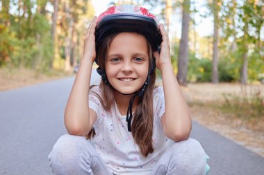Yaz boyunca parkta kask takıp asfalt yolda doğa ile çevrili dışarıda spor ve spor yapmak.