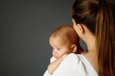 Anne, yeni doğan oğlunu sevgiyle kucaklıyor. Bebek büyümeye ve şefkate teşvik etmeye çalışıyor. Küçük kızını sevgi dolu bir şekilde duvara yaslıyor.