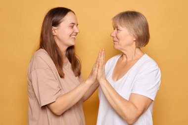 Sıcak, canlı, sarı bir ortamda, genç bir kadın ve yaşlı bir kadın canlı bir değiş tokuşa girişiyor, neşe ve sıcaklık ifade ederken göz temasını sürdürüyor ve birbirlerine gülümsüyorlar..