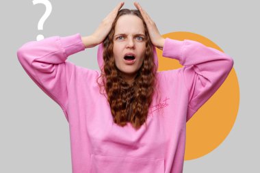 Pembe kapüşonlu genç bir kadın şaşkın bir ifade sergiliyor, elleri kafasının üstünde, sanki kafası karışmış gibi. Ayar gri arkaplan ve belirgin turuncu daire ile minimalistik..
