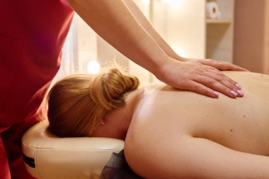 Yetenekli bir terapist, sakin bir spa ortamında müşteriye rahatlatıcı bir sırt masajı sağlar. Sıcak aydınlatma, tedavi sırasında huzurlu ortamı geliştirir..