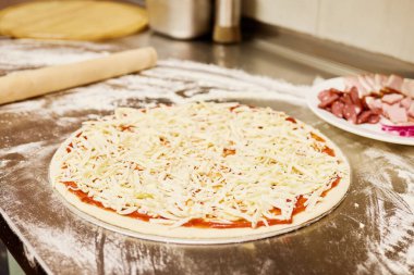 Hamur, un kaplı bir tezgahın üzerine yuvarlanır ve yanında malzemelerle dolu bir tabak bulunur. Mutfak sıcak ve davetkar. Lezzetli bir yemek yapmak için mükemmel..