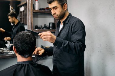 Yetenekli bir berber, berber koltuğunda oturan bir müşterinin saçını dikkatlice şekillendirir. Modern salon aletlerle donatılmıştır ve parlak, çağdaş bir tasarıma sahiptir..