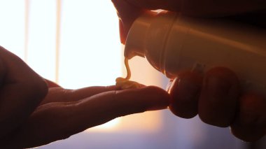 Yumuşak güneş ışığı pencereden içeri akarken eller avuç içine nemlendirici döker ve sıcak ve davetkar bir atmosfer yaratır..