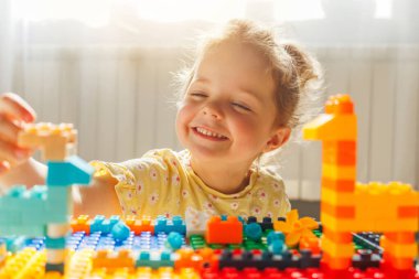 Neşeli genç kız renkli oyuncak blokları ve hayvan figürleriyle oynayarak çocukluk yaratıcılığını, eğlencesini ve hayal gücünü yakalıyor..