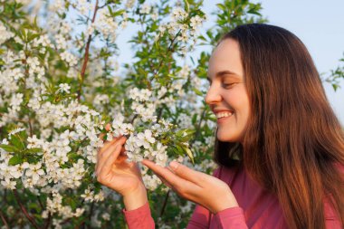 Gülümseyen kadın beyaz çiçeklerden hoşlanır, mutlu ve alerjisi yoktur, ilkbaharda doğanın güzelliğini takdir eder..