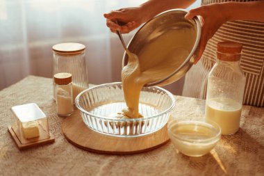 Çizgili önlüklü bir aşçı, metal bir kaseden kalın bir hamuru cam bir turta tabağına döker..