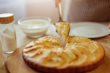 Çizgili önlüklü bir aşçı, bir dilim taze pişmiş elmalı turtayı bir spatulayla kaldırır..