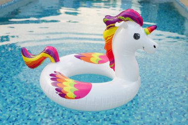 Parlak, şişme tek boynuzlu at rengarenk yelesi ve parlak mavi yüzme havuzunda kuyruğu sallanan..