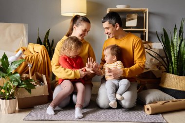 Mutlu bir aile ve iki çocuk birlikte oynuyorlar. Bir bebek ve bir bebek el ele tutuşuyorlar. Yeni bir evde kutuları taşıyorlar..