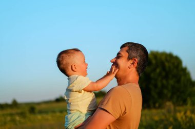 Parlak renkli gökyüzü, baba ve oğlu arasında akşam saatlerinde güzel bir açık hava ortamında neşeli bir anın altını çiziyor..