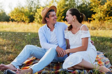 Tarlada piknik yapan, el ele tutuşan ve gülen bir çift..