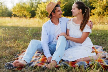 Romantik genç bir çift piknik yapıyor ve güneşli bir günün tadını çıkarıyor..