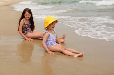 İki mutlu çocuk kumsalda keyifli bir günün tadını çıkarıyorlar. Kumsalda oynuyorlar ve ılık güneşin altında hafif dalgalarda yüzüyorlar..