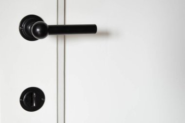Art deco black metal door handel on white wooden door