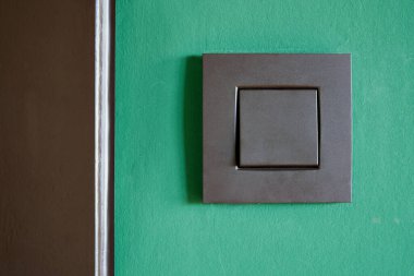 Close-up of a Black light switch on green wall view from front 