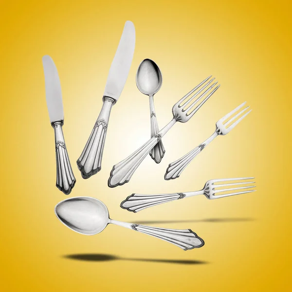 Floating Old Silverware Set  with shadows on orange gradient background